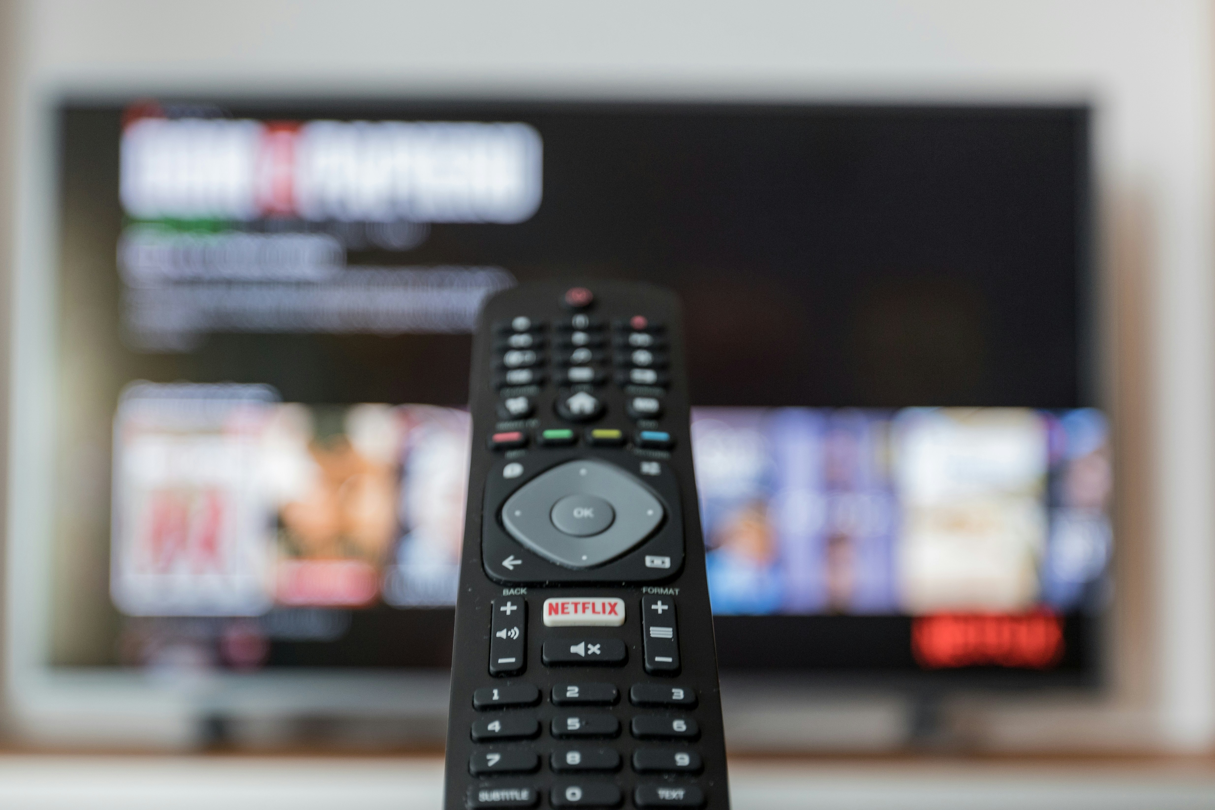 Remote control on coffee table with 4K television in background